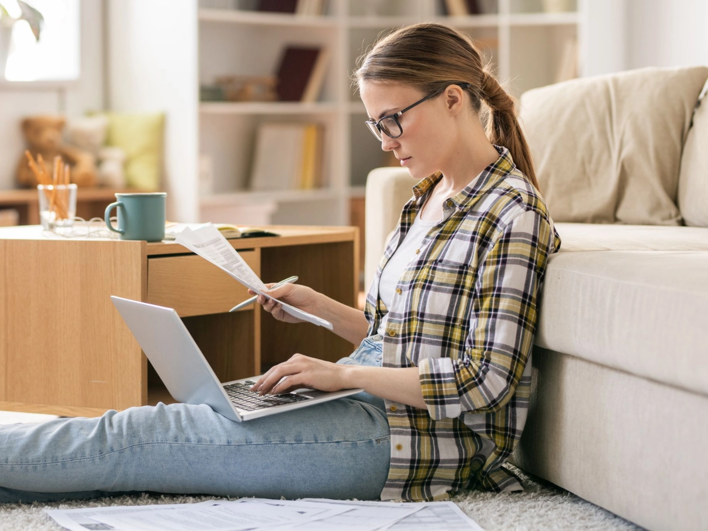 Junge Frau arbeitet mit Laptop auf dem Fußboden