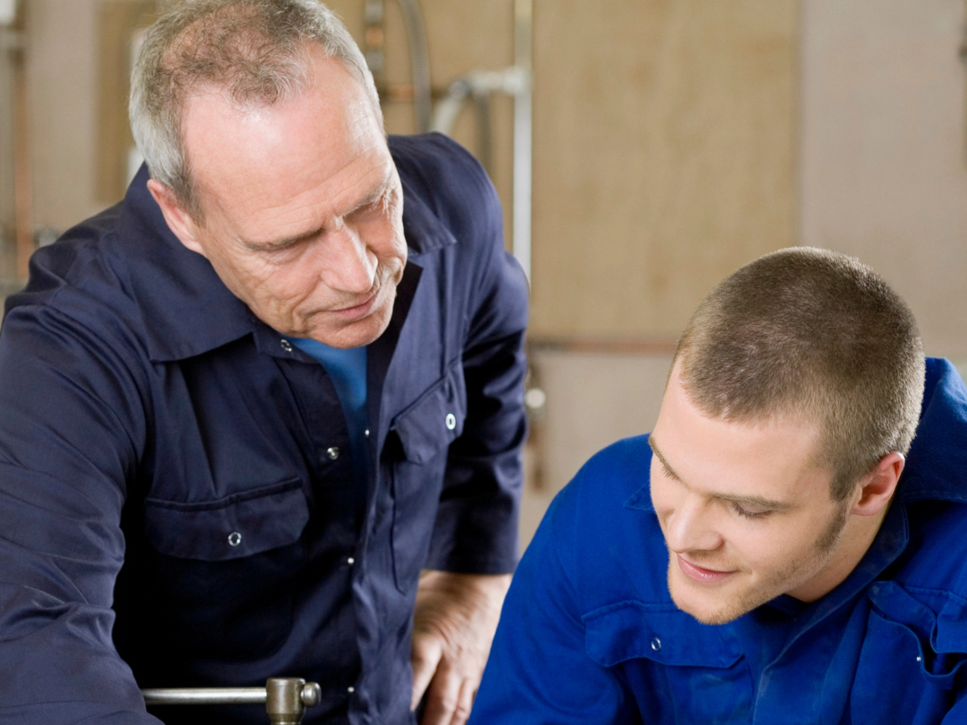 Ein Auszubildender zum Gas-Wasser Installateur bekommt von seinem Meister etwas erklärt.