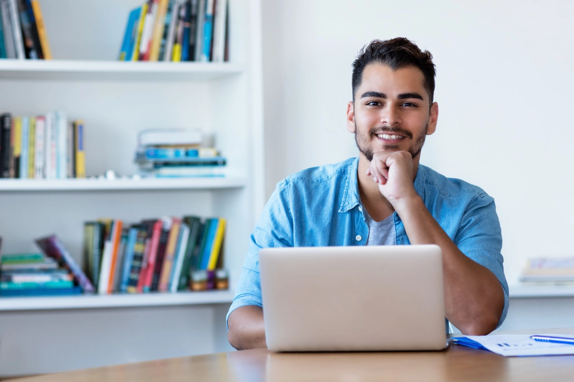 junger Mann sitzt mit einem Laptop zu Hause am Tisch