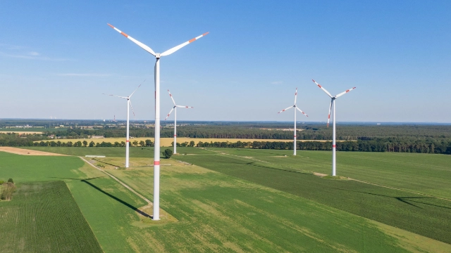 mehrere Windkraftanlagen bei gutem Wetter auf grüner Wiese