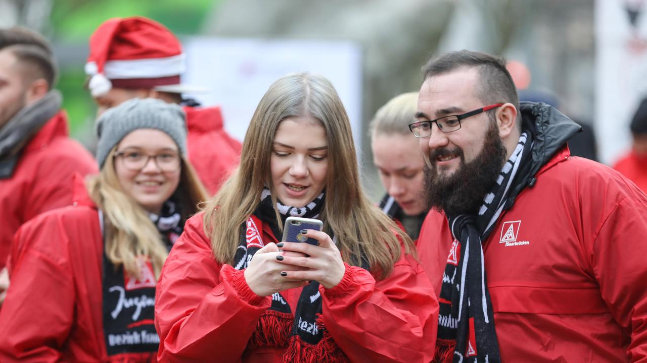 Junge Frau tippt in ihr Handy. Ein Junger Mann schaut mit auf das Gerät.