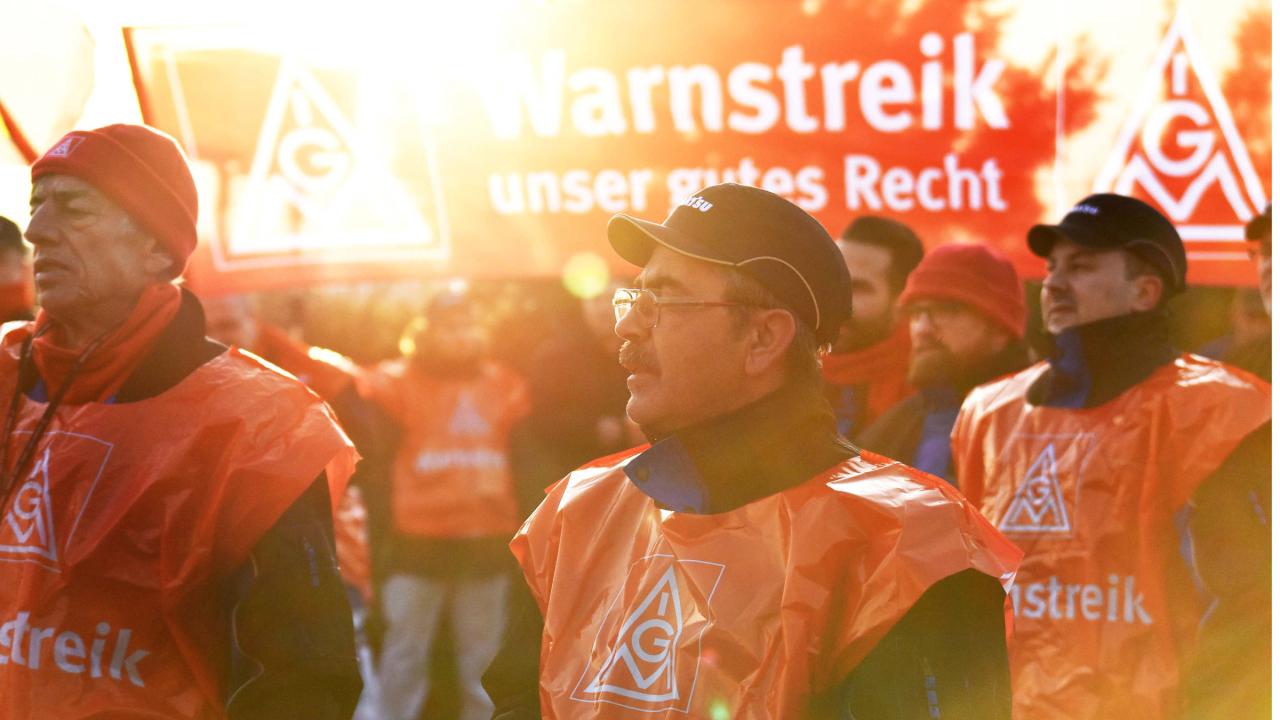 Eine Gruppe streikende Männer wird von der Sonne angestrahlt.