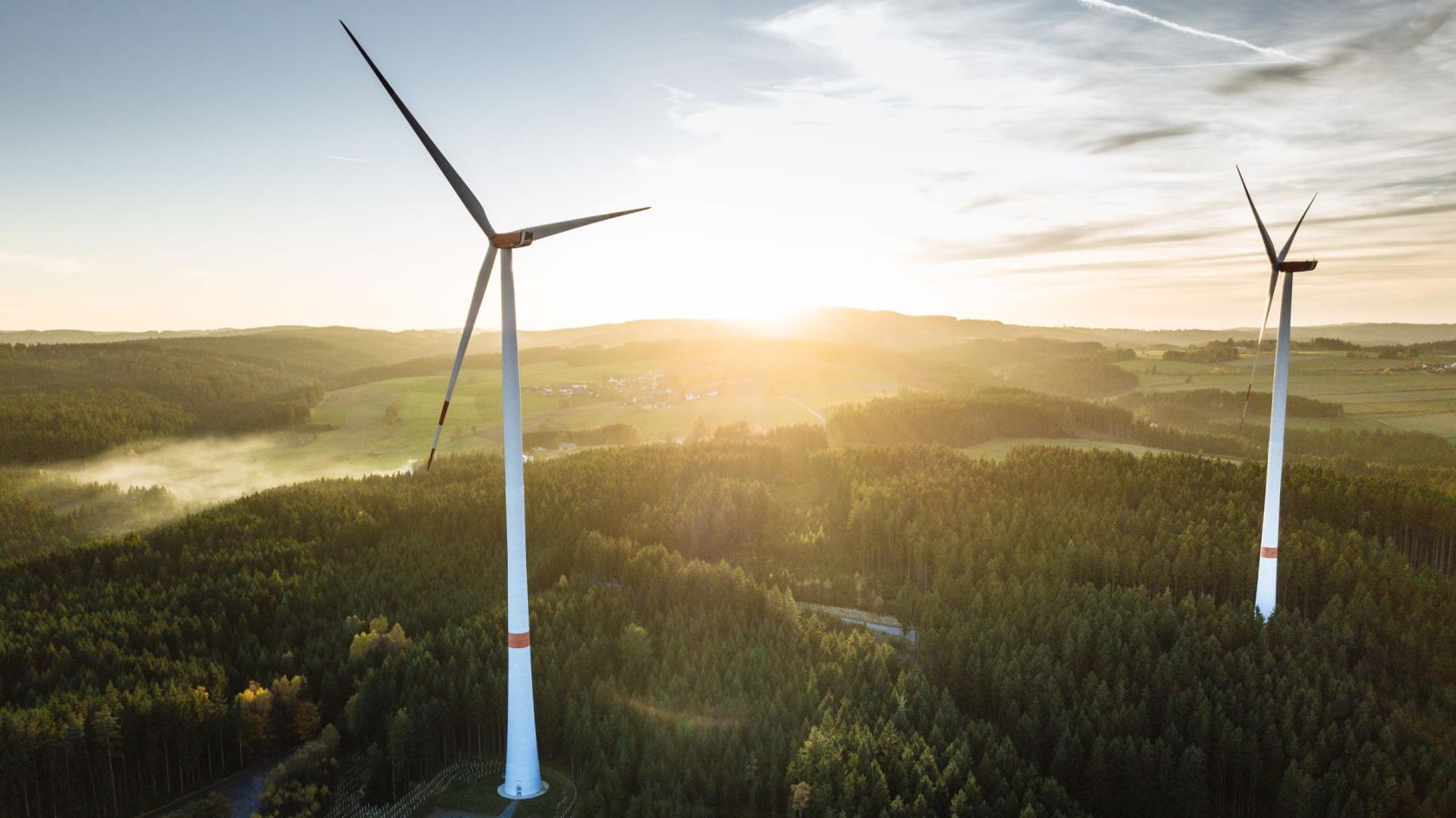 zwei Windkraftanlagen während eines Sonnenuntergangs